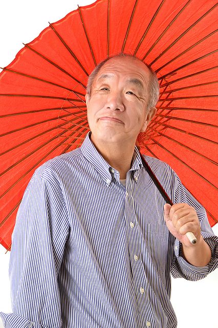 赤色の番傘を片手にポーズを取る鈴木義晴（2021.11.112）スプラッシュ