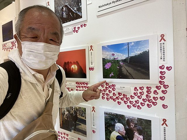 第三回西東京百姿写真展の受賞作品を指さす鈴木義晴（2022.4.30）
