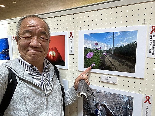 第３回西東京百姿の受賞作品を前に自撮りする鈴木義晴（2023.4.16）スプラッシュ