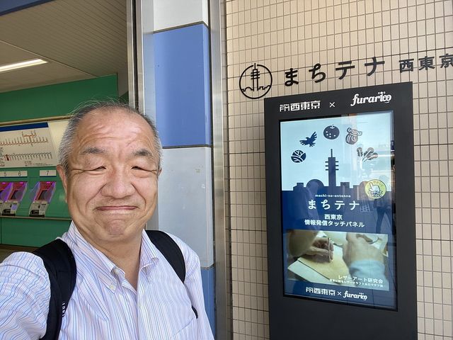 田無駅北口前のまちテナ西東京を背に自撮りする鈴木義晴